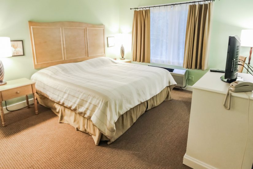Photo of bedroom with bed, dresser, side tables and television